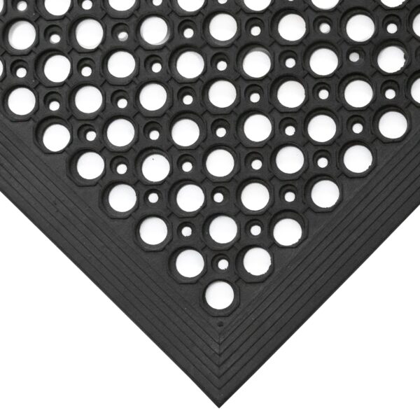 Close-up of the Large Front Door Mat Bundle’s corner, showing black rubber with circular holes in a repeating pattern and bevelled edges for a smooth floor transition.