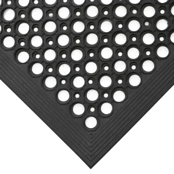 Close-up of the Large Front Door Mat Bundle in black rubber, featuring a pattern of large and small circular holes. The image captures the corner with its textured, layered border and durable design.