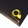 A yellow wired device with a clip is coiled and placed on a Bubble Top ESD Mat, featuring a textured black rubber surface with raised circular bumps.