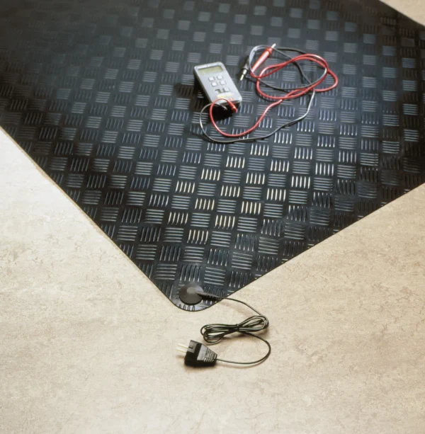 A Senso Dial Mat ESD, a black textured heating mat with digital thermostat and wires, is placed partly on a tiled floor with its power plug and lead nearby.