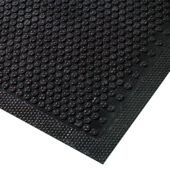 Close-up of the Dirt Remover Mat, featuring black rubber with raised circular bumps and a textured border, viewed from an angle.