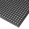 Close-up view of the Honeycomb Kitchen Mat, a black rubber mat featuring regularly spaced circular holes for superior grip and drainage. The angled image highlights the mat’s thickness and textured surface.