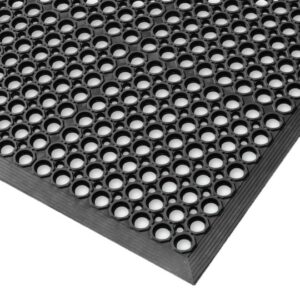Close-up view of the Honeycomb Kitchen Mat, a black rubber mat featuring regularly spaced circular holes for superior grip and drainage. The angled image highlights the mat’s thickness and textured surface.