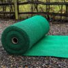 A large roll of Heavy-Duty PVC Vinyl is unrolled outdoors on gravel, with a wooden fence and grassy area visible in the background.