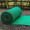 A large Heavy-Duty PVC Vinyl Roll unrolled on a gravel surface outdoors, with a wooden fence and greenery visible in the background.