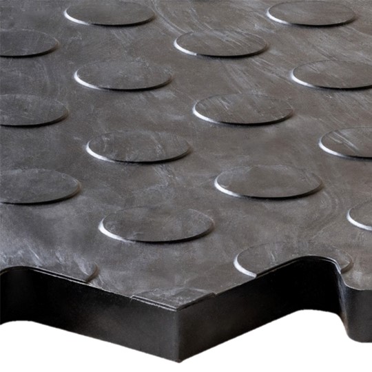Close-up of the Circular Stud Interlocking Tile, a black rubber flooring mat featuring a raised circular stud pattern and zigzag cut edge detail.