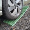 A car tyre rests on Waffle Boards, green plastic traction mats placed on gravel to help prevent the vehicle from getting stuck.