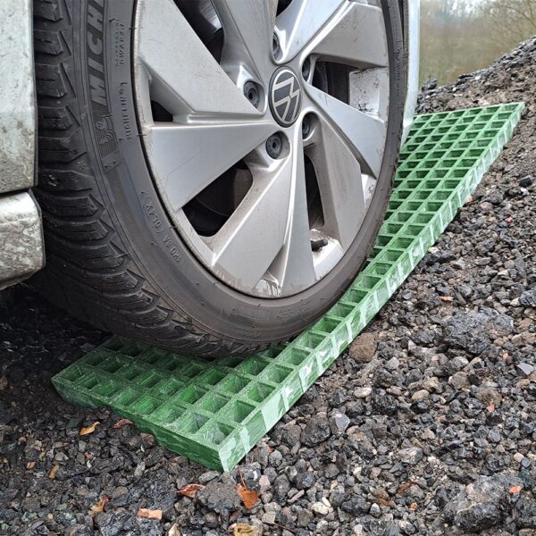 A car tyre rests on Waffle Boards, green plastic traction mats placed on gravel to help prevent the vehicle from getting stuck.