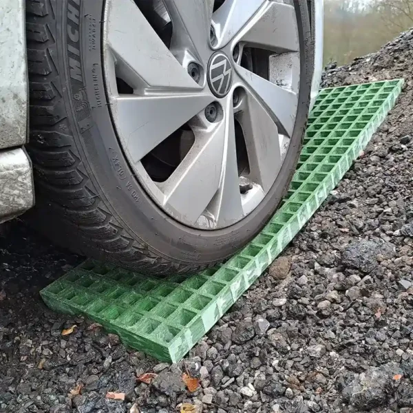 A car tyre rests on Waffle Boards traction mats placed on gravel, likely to help the vehicle gain grip on the uneven surface.