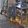 In a workshop, a person in protective gear welds metal at a workbench as bright sparks fly, standing on the Welding Anti-Fatigue Mat for comfort and safety.