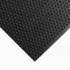 A close-up of the Bubble Top Stable Mat, a black rubber mat featuring raised circular bumps, is placed on a white surface. Photographed at an angle, the image highlights its textured surface and geometric pattern.