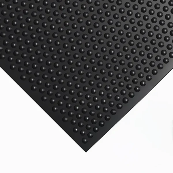 A close-up of the Bubble Top Stable Mat, a black rubber mat featuring raised circular bumps, is placed on a white surface. Photographed at an angle, the image highlights its textured surface and geometric pattern.