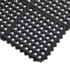 The Interlocking Anti-Fatigue Mat is made of black rubber featuring a grid pattern of large circular holes and raised edge bumps, displayed from an angled top-down view.