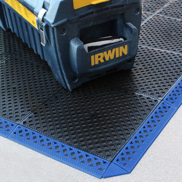 A blue IRWIN toolbox sits on a black and blue Multi-Purpose Interlocking PVC Tile with a diamond pattern, placed on a light grey concrete floor.