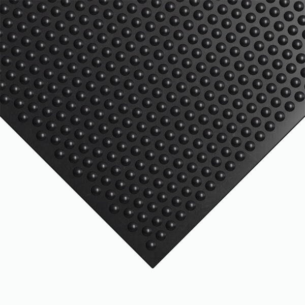 A close-up of the corner of a Stable Matting Bundles black rubber mat featuring raised, evenly spaced circular bumps on its surface.