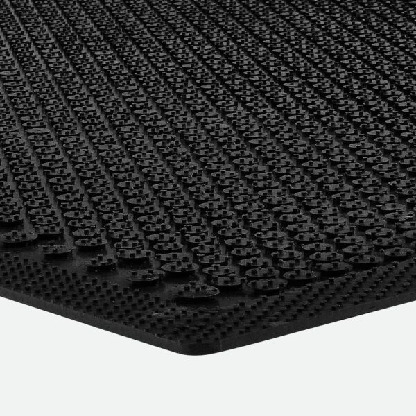 Close-up of the Dirt Remover Mat, a black rubber mat featuring a textured, raised circular pattern, displayed at an angle against a white background.