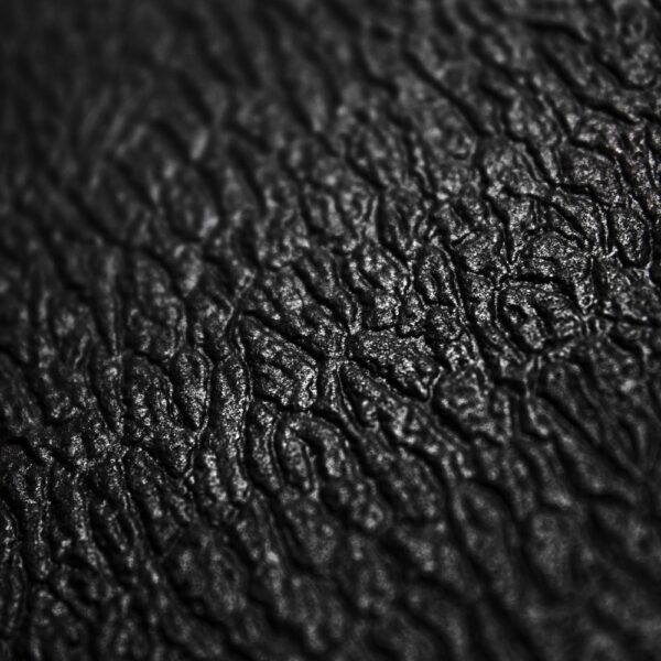Close-up of the Standard Anti-Fatigue Mat's textured black surface, featuring deep, irregular grooves and a slightly shiny finish that resembles leather or skin.