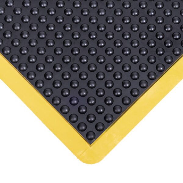 Close-up of the Interlocking Air Cushioned Mat in black rubber, featuring raised circular bumps and a yellow border at the corner.
