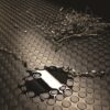A puddle and dry twigs rest on Circular Stud Rubber Matting, whose textured black surface features circular patterns. Reflected light from the wet area contrasts with the matt background of the matting.