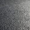 Close-up view of the Amoebic Top Stable Mat’s textured grey surface featuring a wavy, irregular pattern and slight reflectivity, resembling embossed metal or rubber flooring.