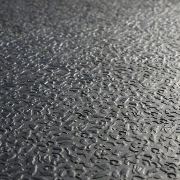 Close-up view of the Amoebic Top Stable Mat’s textured grey surface featuring a wavy, irregular pattern and slight reflectivity, resembling embossed metal or rubber flooring.
