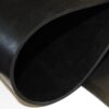 A close-up image of the Commercial Neoprene Rubber Sheet, showing its thick, flexible black material curled to reveal a smooth surface and sturdy texture.