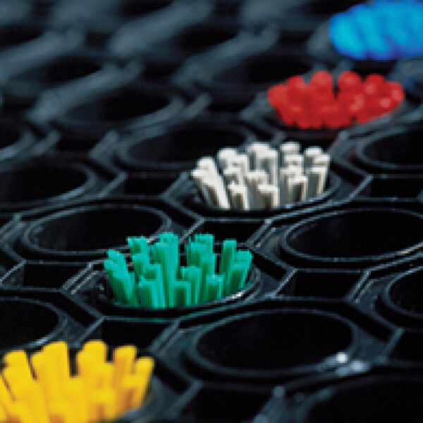 Close-up of an Octagonal Ring Mat featuring textured black material and clusters of yellow, green, white, red, and blue bristles arranged in octagonal openings. The image highlights the vibrant bristles in the foreground.